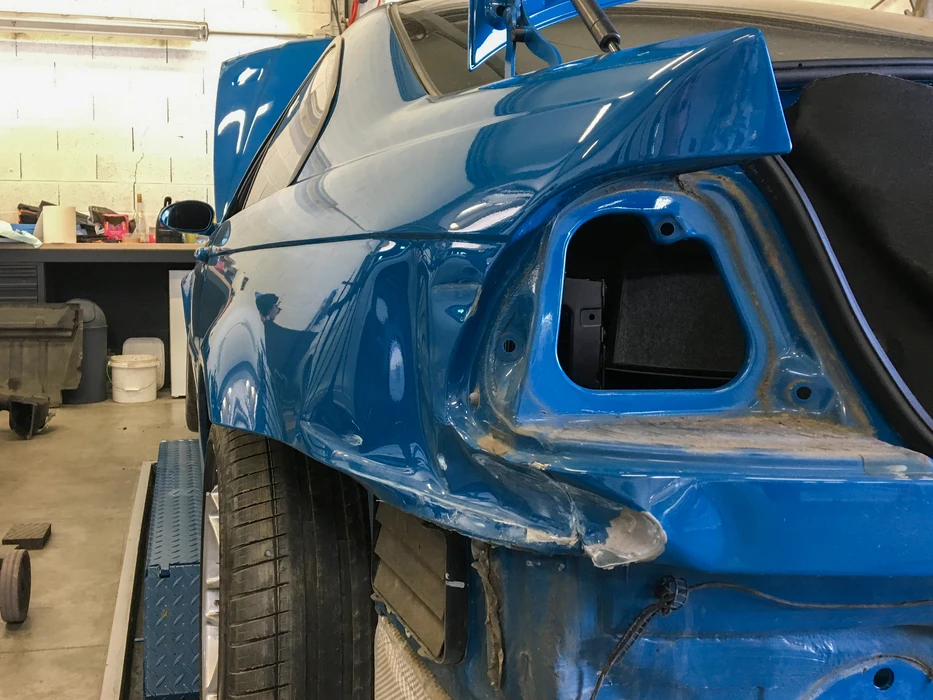 Carrosserie bleue d'un véhicule en atelier de réparation, posé sur un pont élévateur