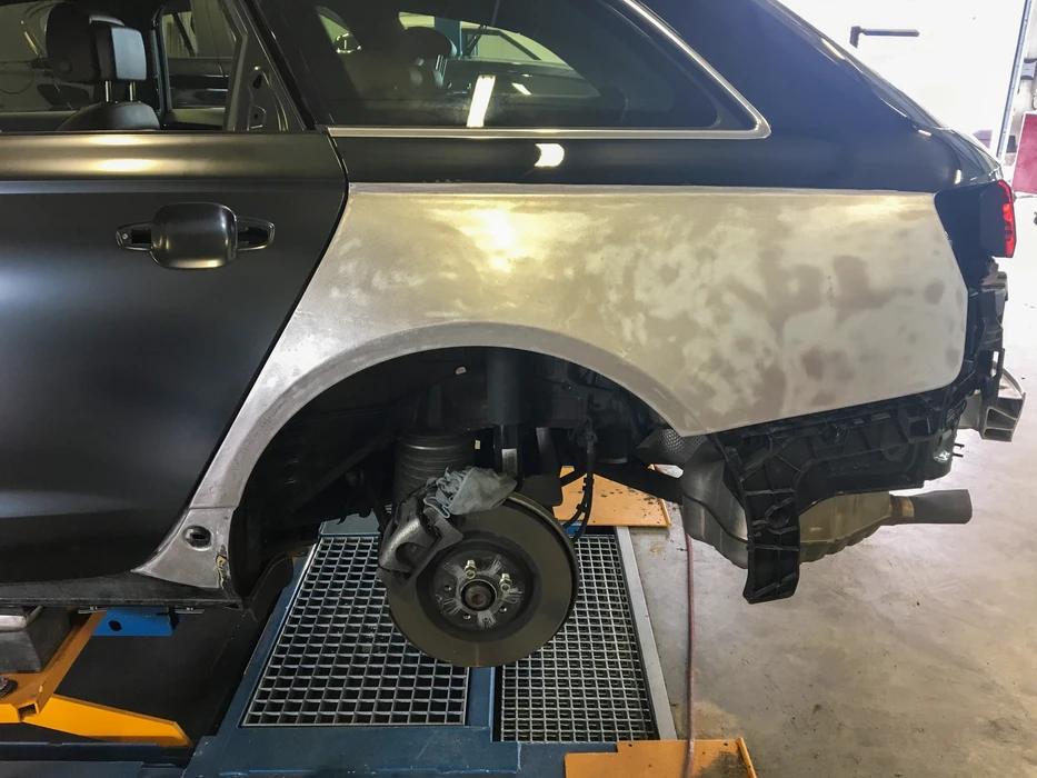 Carrosserie arrière d'un véhicule en réparation dans un atelier, soulevé sur pont élévateur