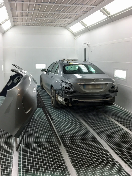 Cabine de peinture professionnelle avec une Mercedes-Benz Classe C gris métallisé en cours de préparation carrosserie