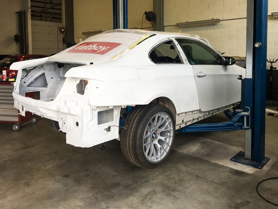 Carrosserie de berline en cabine de peinture professionnelle, masquée avec du papier kraft et ruban adhésif de masquage jaune