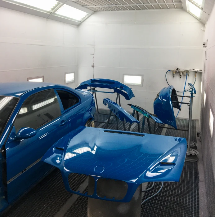 Carrosserie bleue d'un véhicule en atelier de réparation automobile, positionnée sur un élévateur