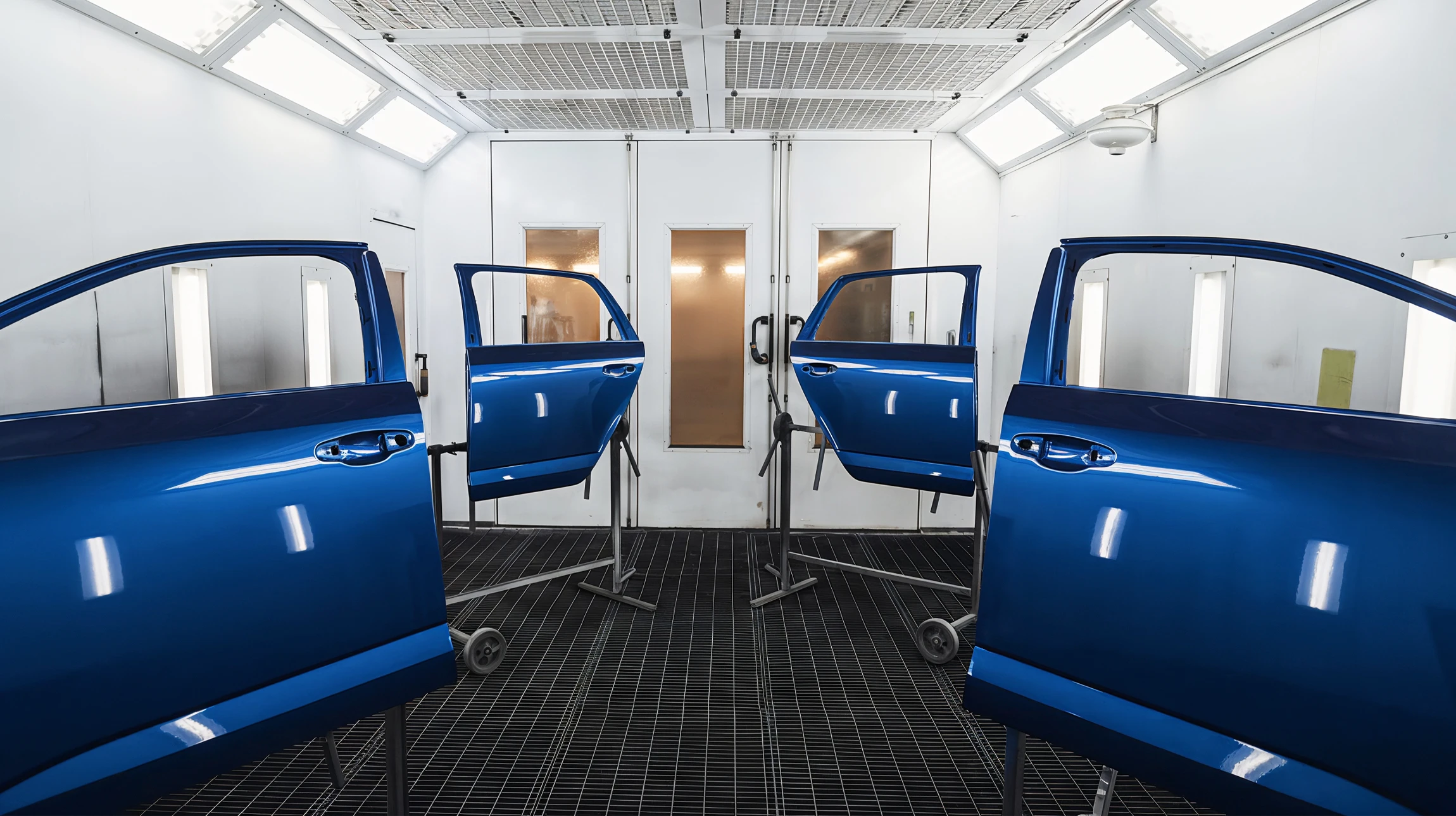 Atelier de carrosserie automobile avec technicien en combinaison de protection appliquant de la peinture blanche sur véhicule